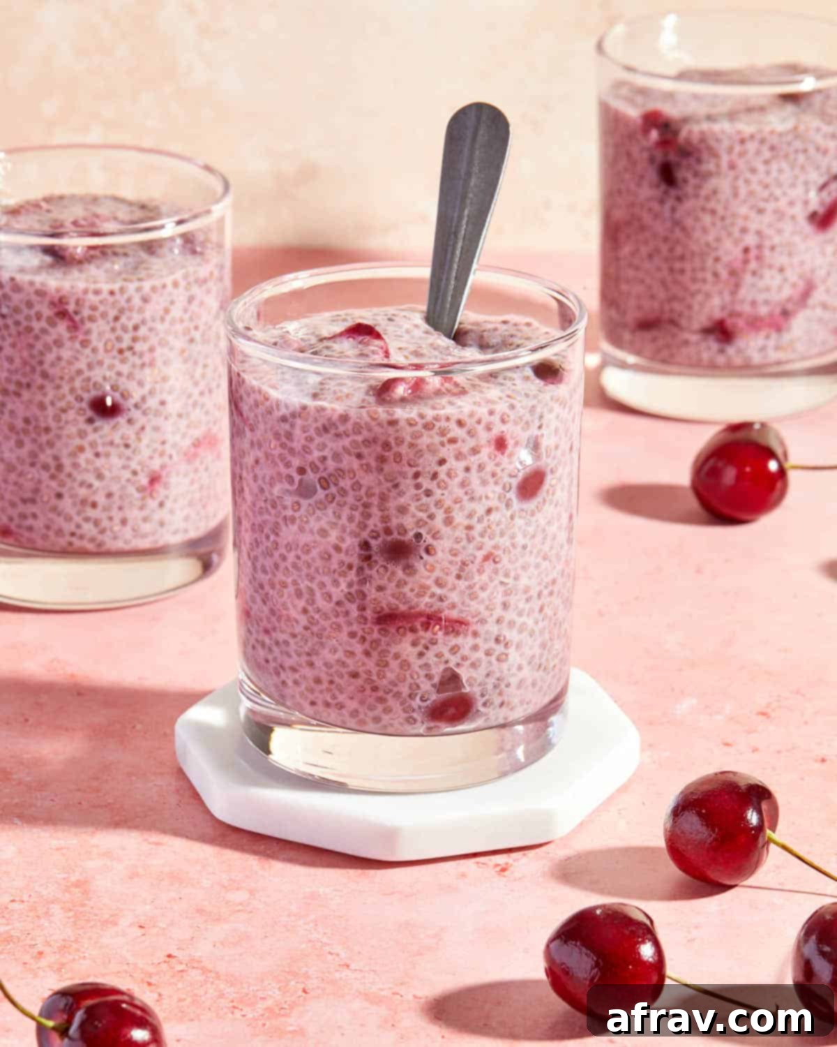 Delicious Dairy Free Gluten Free Cherry Chia Pudding 2 Side view of cherry chia pudding served in glasses on a pink backdrop.