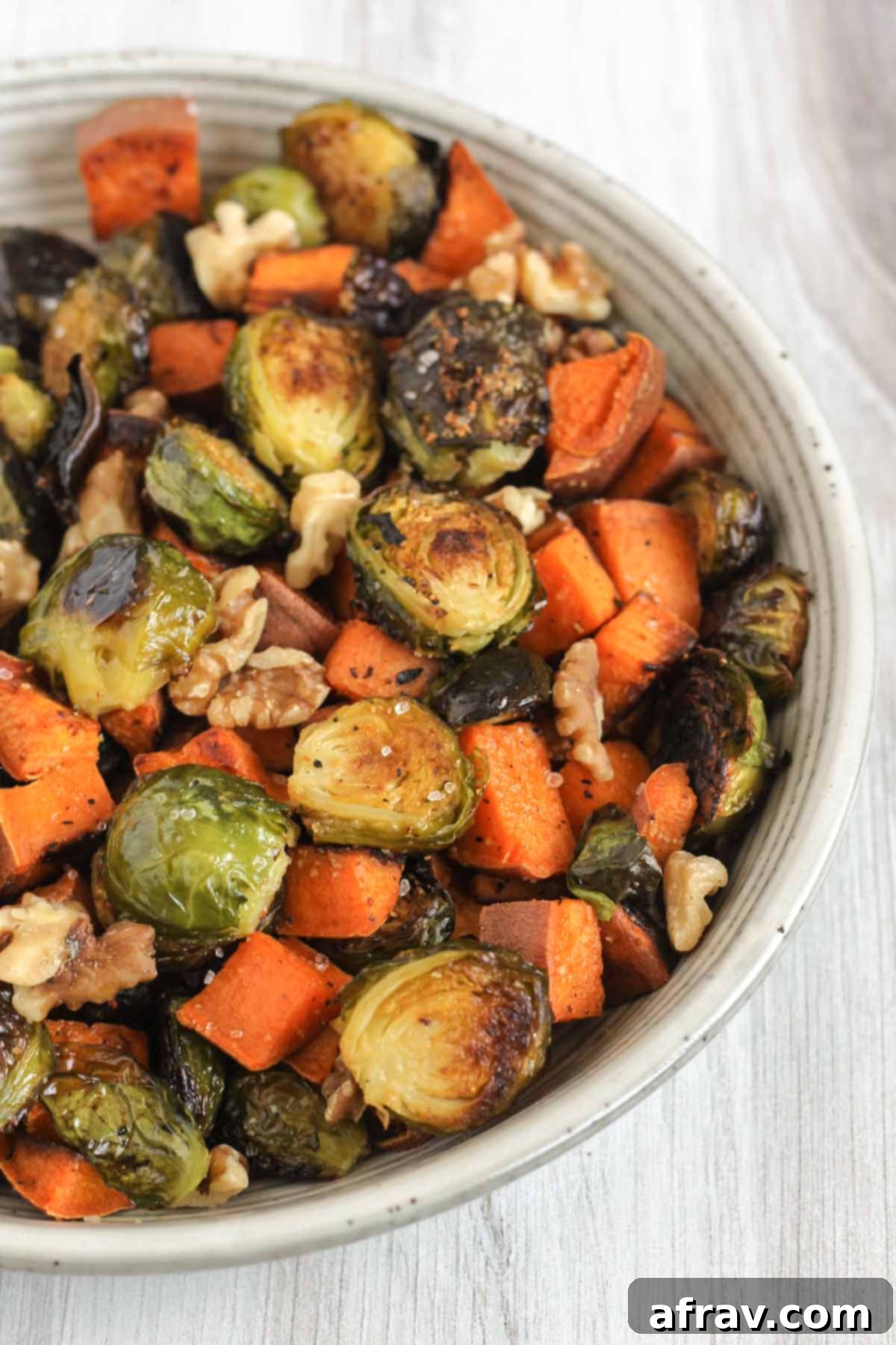Close up of oven roasted sweet potatoes and Brussels sprouts sprinkled with sea salt and walnuts.