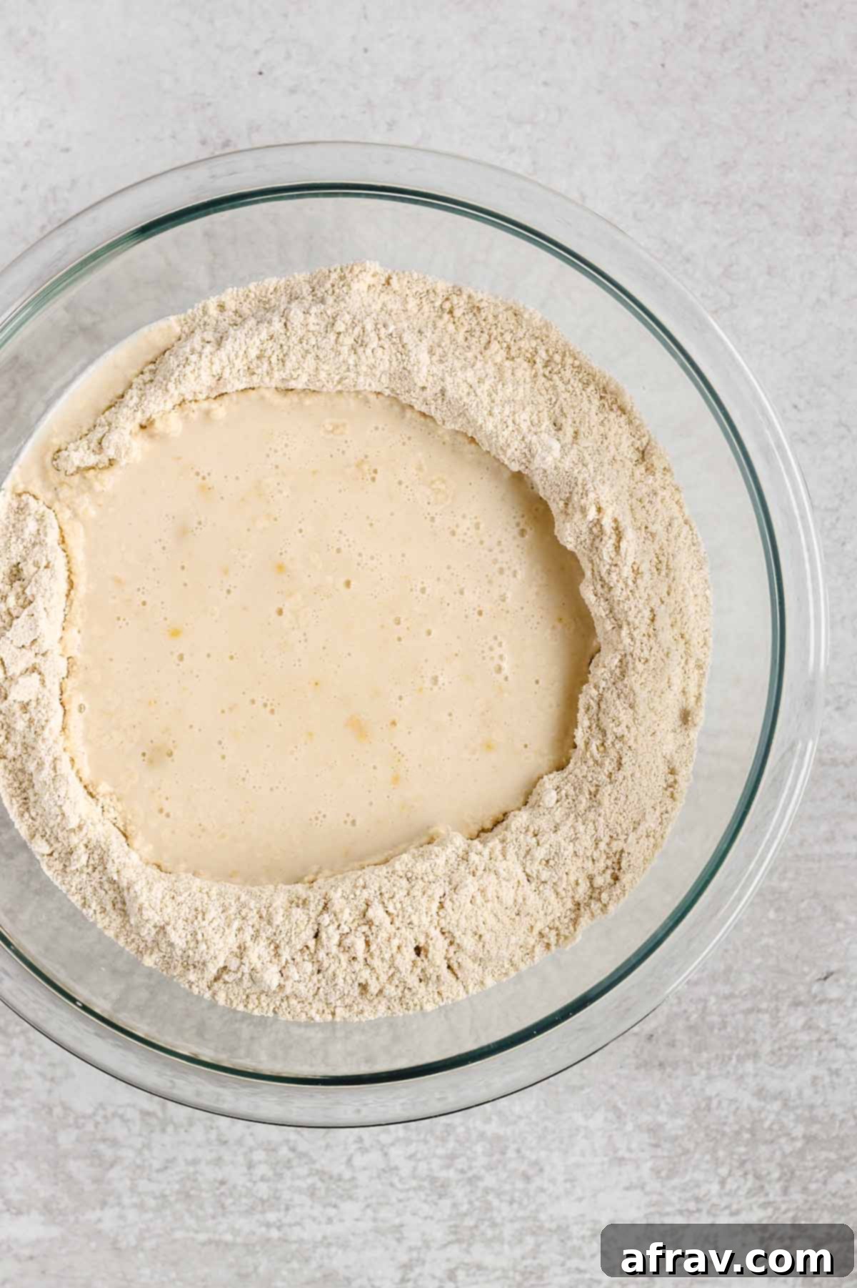 Dry ingredients and wet ingredients needed for gluten-free waffles in a glass mixing bowl.