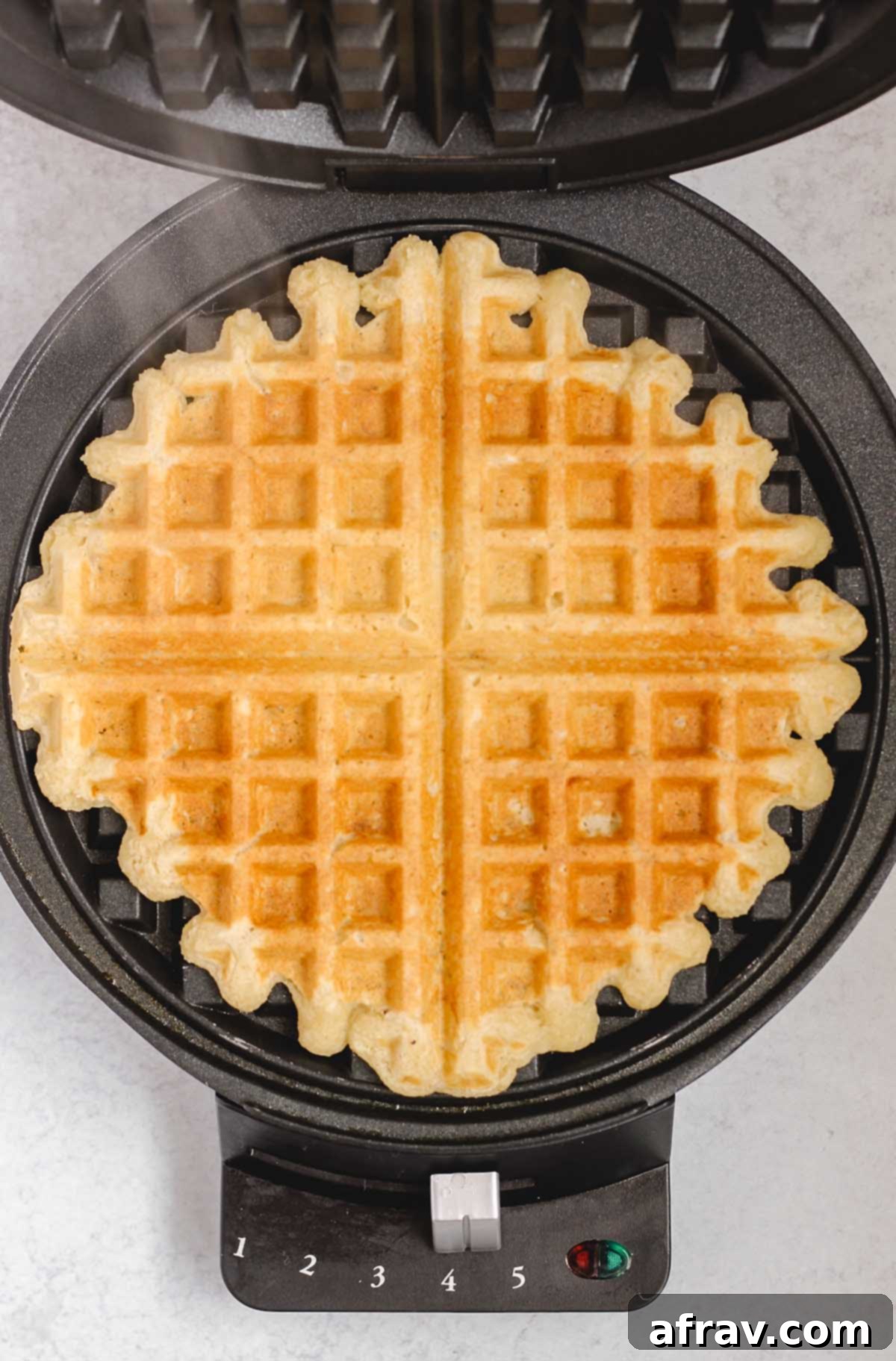 Deliciously Free Waffles 7 A perfectly cooked, golden-brown gluten-free waffle revealed within a waffle iron, steam gently rising.