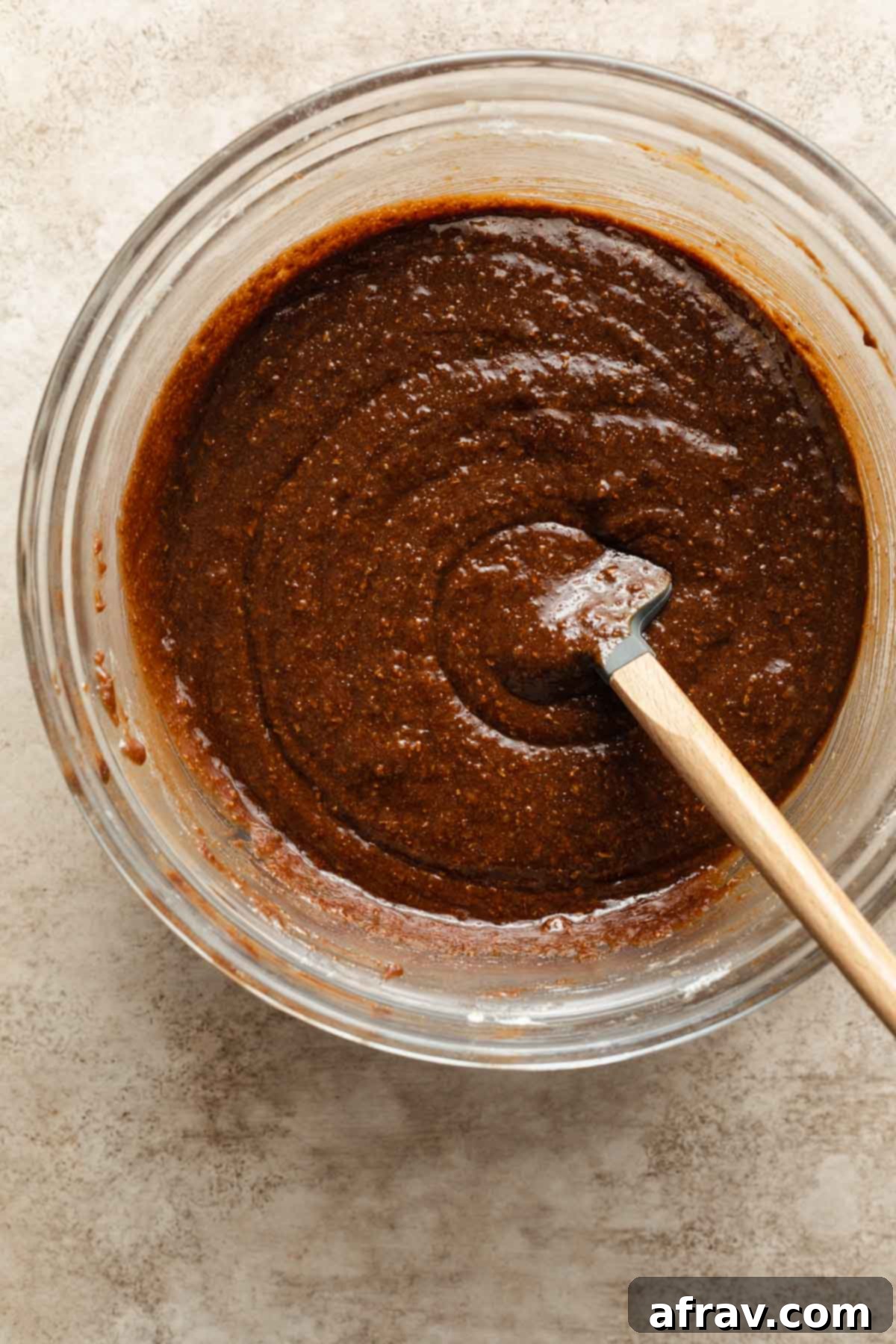 Decadent Dairy-Free Almond Butter Brownies 5 Almond butter brownie batter being stirred in a glass bowl with a spatula.