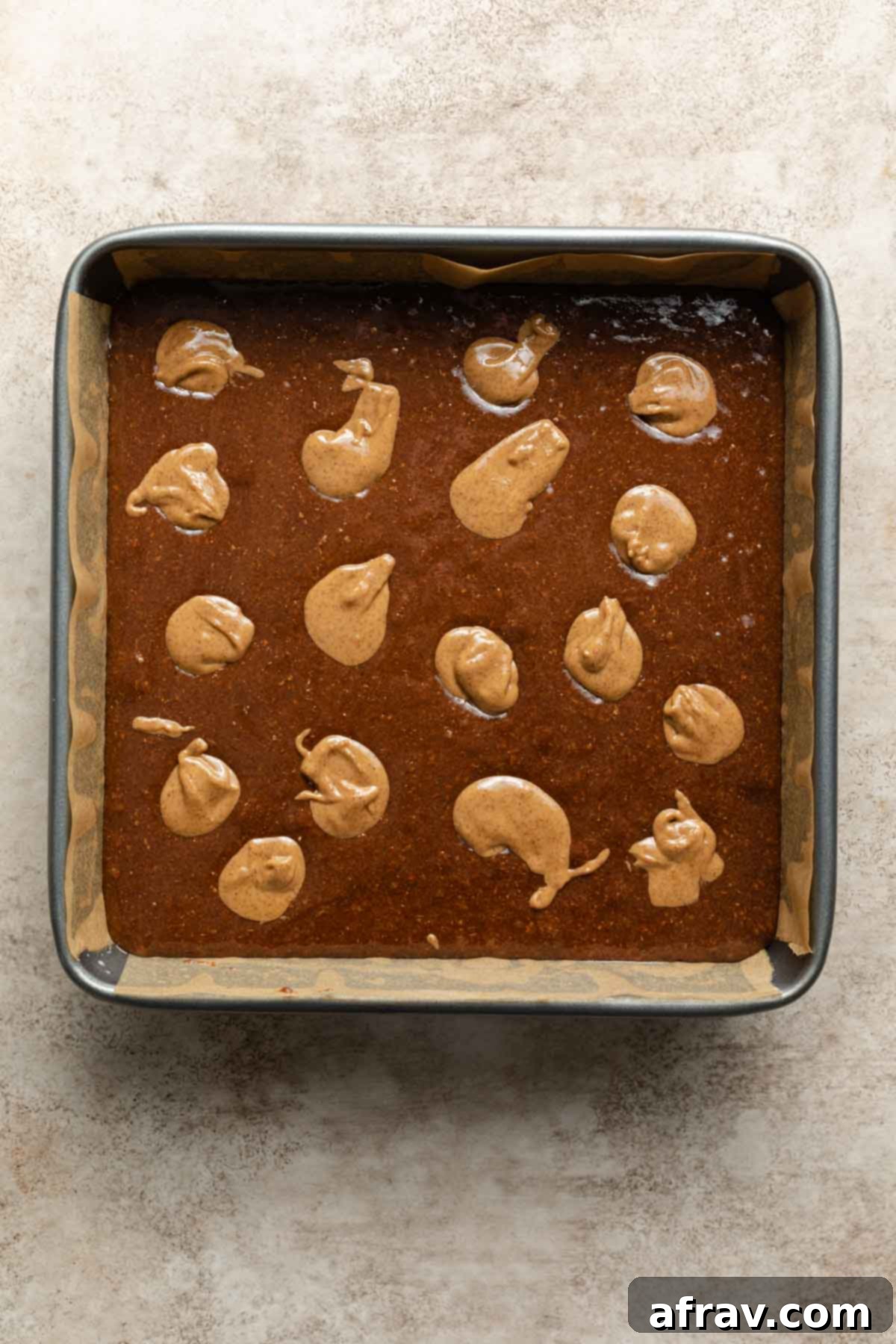 Decadent Dairy-Free Almond Butter Brownies 6 Brownie batter in a pan with dollops of almond butter on top.