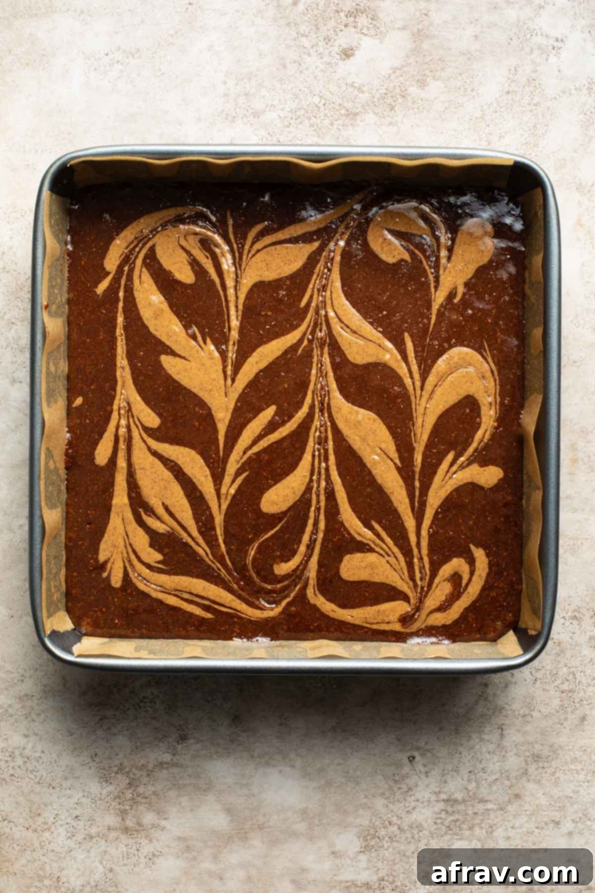 Decadent Dairy-Free Almond Butter Brownies 7 Brownie batter in a square pan with almond butter swirled around on top.