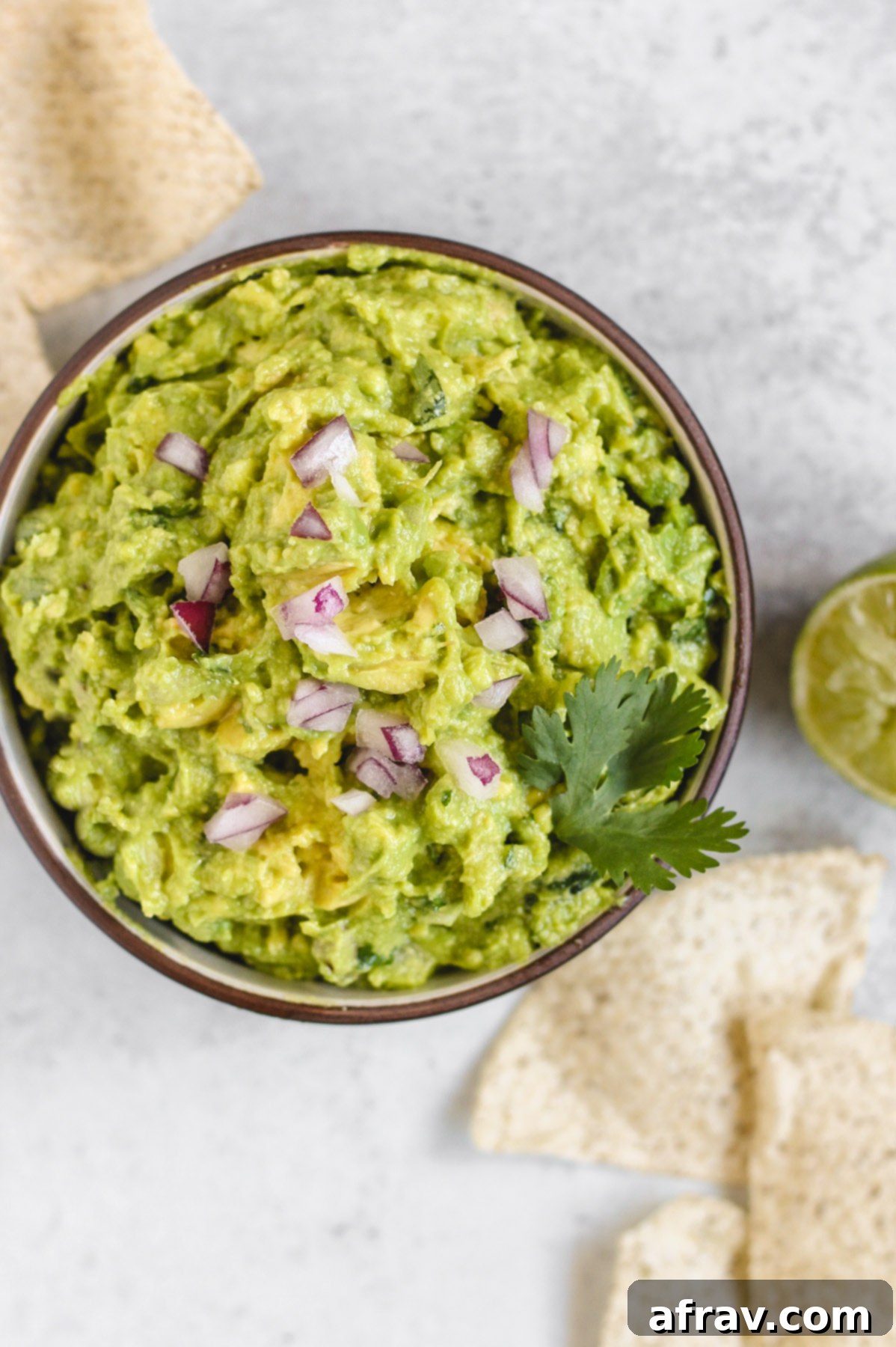 overhead view of guacamole in a serving bowl with chips sprinkled on the side
