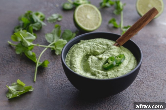 Up-close view of creamy jalapeño dip in a small bowl with a serving spoon.