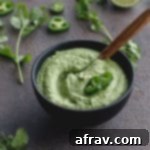 Creamy Jalapeño Dip in a small bowl on a grey surface with a serving spoon inserted into the bowl.
