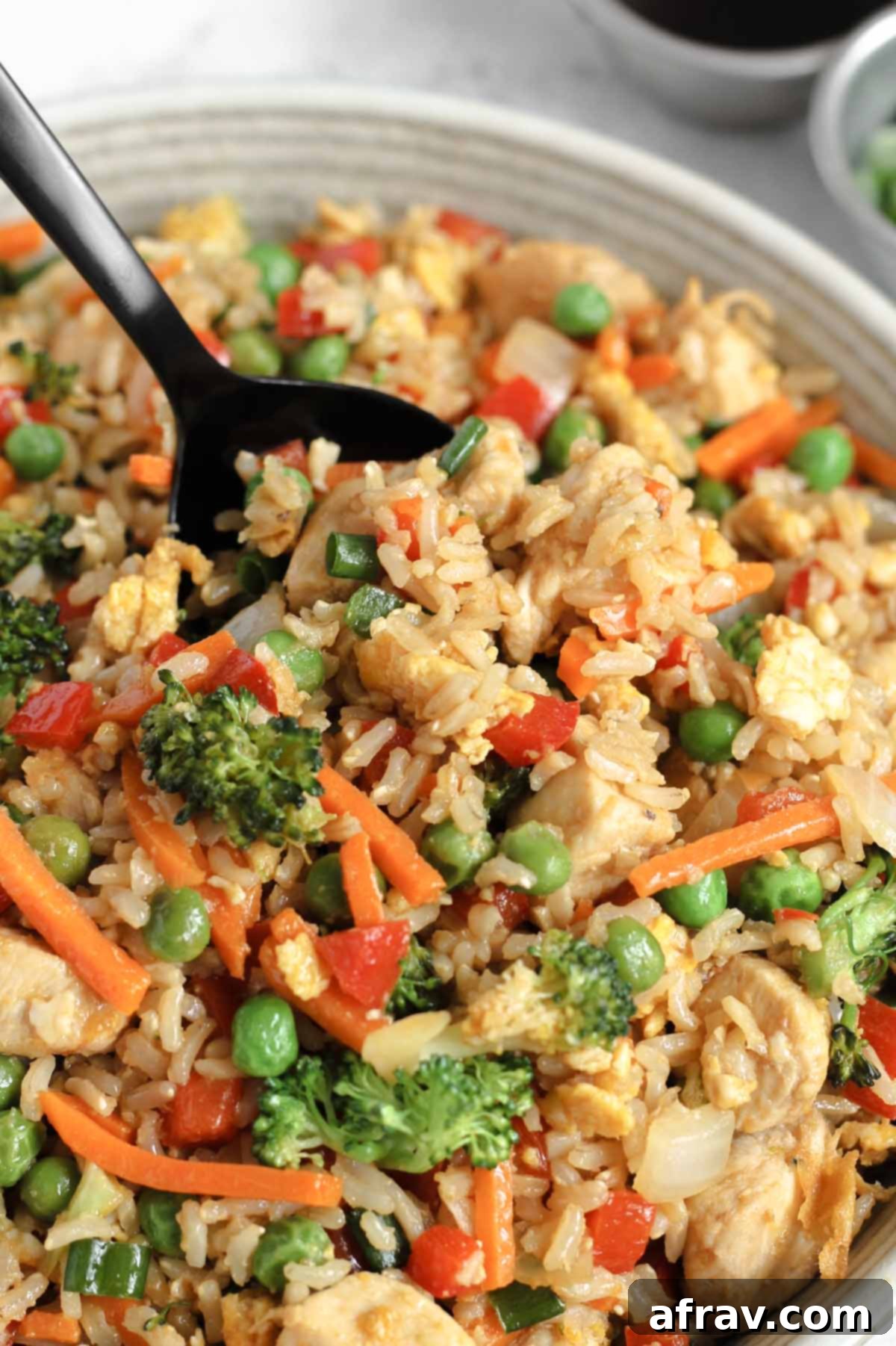 Close-up of a spoon scooping healthy fried rice from a serving bowl.