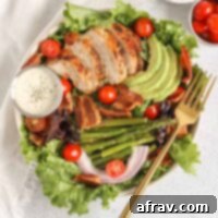 BLT Bliss Chicken Salad 7 A beautifully arranged salad bowl, showcasing the BLT chicken salad with tender chicken, crispy bacon, creamy avocado, fresh asparagus, and ripe tomatoes, served alongside a ramekin of dairy-free ranch dressing.