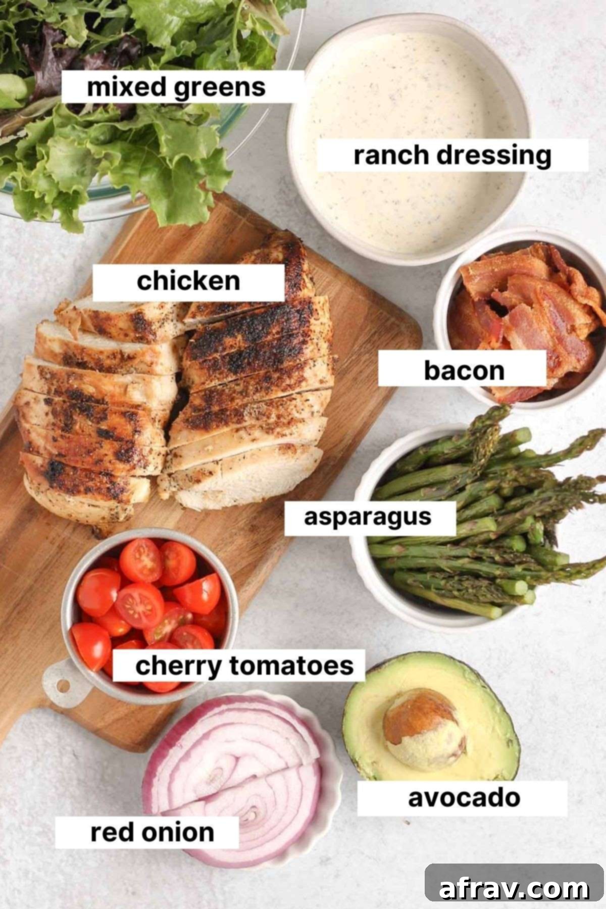 BLT Bliss Chicken Salad 3 Individual ingredients for a healthy BLT chicken salad laid out on a clean counter, including cooked chicken breast, mixed greens, crispy bacon, vibrant cherry tomatoes, roasted asparagus, red onion, and a perfectly ripe avocado.