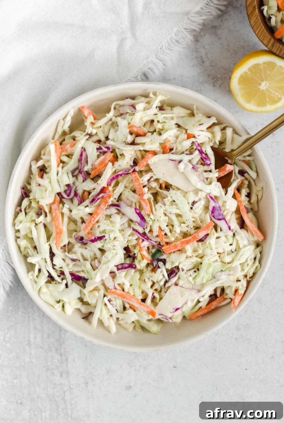 Whole30/Paleo coleslaw in a serving dish with a gold spoon, ready to be enjoyed.