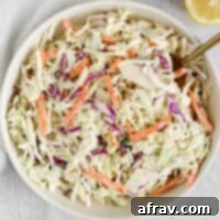 Creamy coleslaw in a serving bowl with a gold spoon, ready to be served.