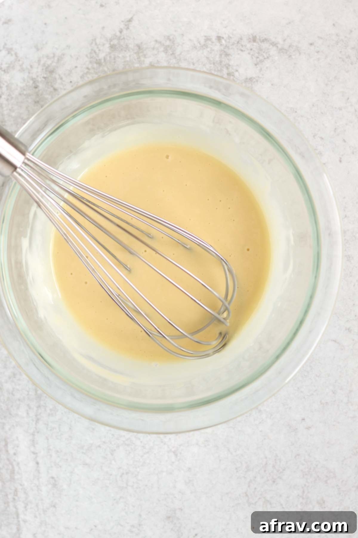 Coleslaw dressing being whisked in a mixing bowl, showcasing the creamy texture.