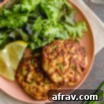 Air Fryer Salmon Patties on a pink plate with some fresh greens.