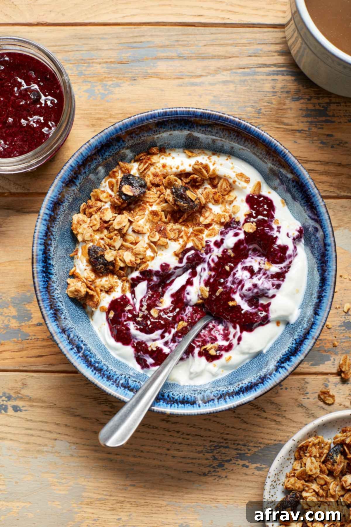 A bowl of creamy yogurt topped with crunchy granola and a beautiful swirl of homemade triple berry chia jam.