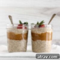 Two mason jars filled with overnight oats and almond butter topped with a strawberry.