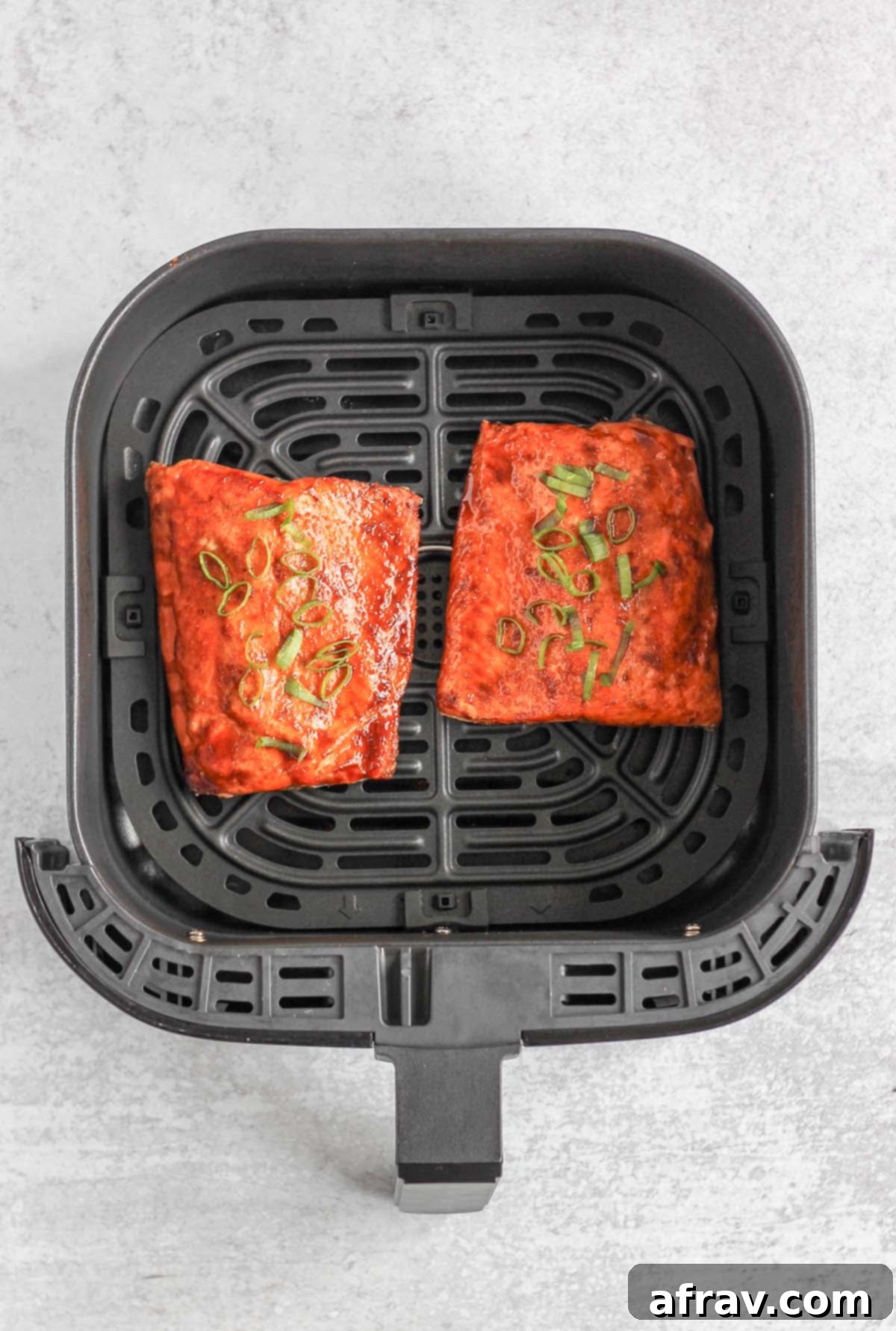Cooked salmon fillets in an air fryer basket.