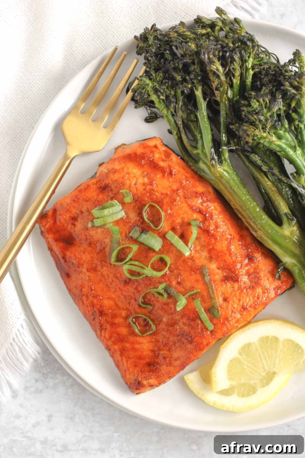 Salmon fillet topped with sliced green onions on a white plate.