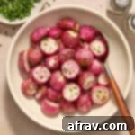 Air fryer radishes served in a white bowl with a spoon and chopped parsley on the side.