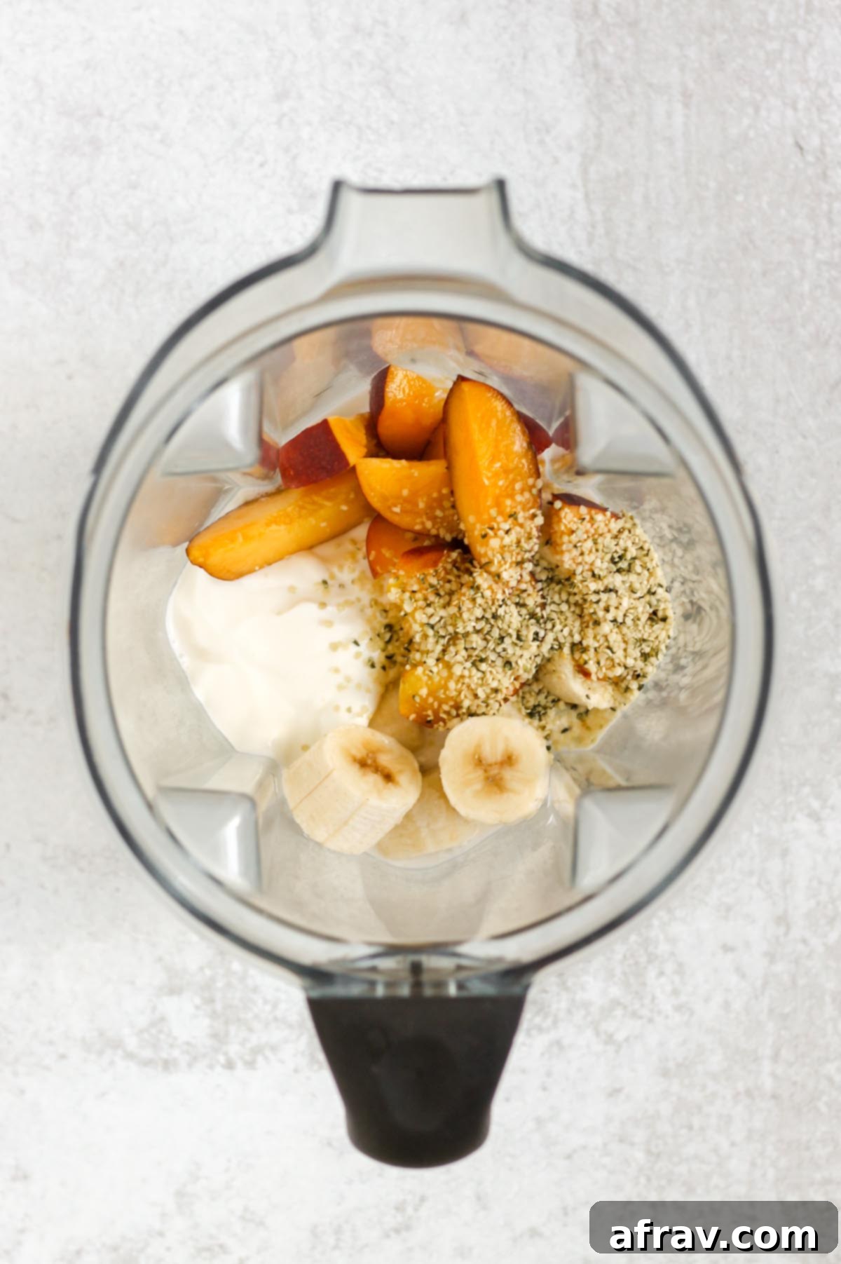 Ingredients for a peach banana smoothie in a blender.