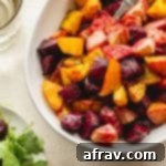 Up close view of air fryer roasted beets in a white bowl with a spoon inserted into the beets.