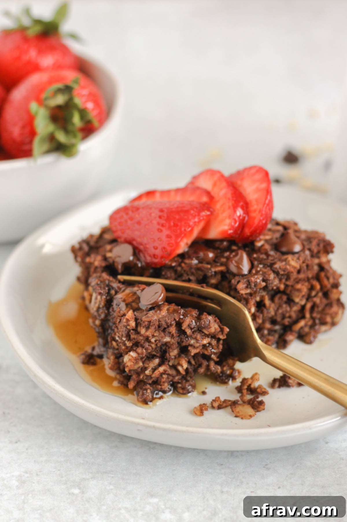 A gold fork cutting a bite off of a piece of chocolate baked oats.