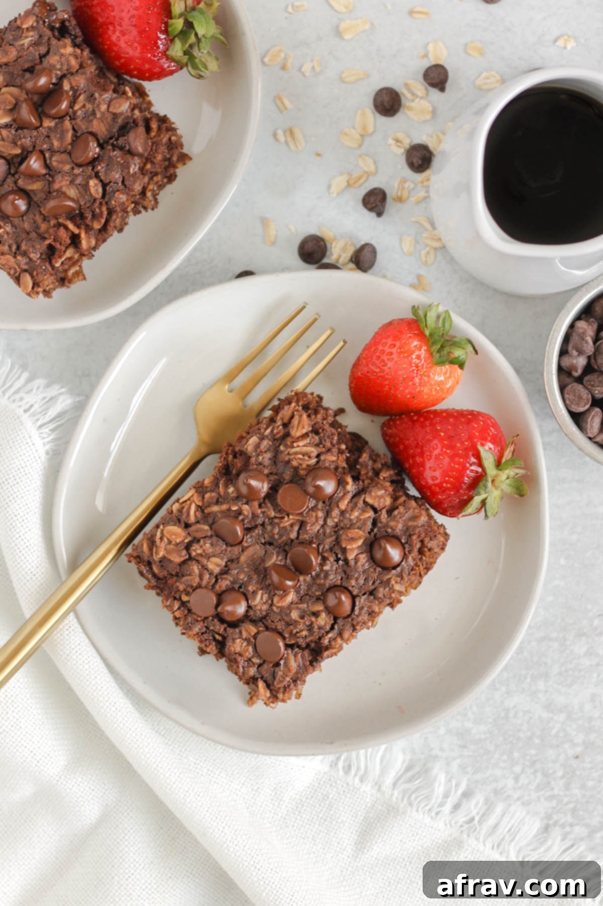 Two plates with square pieces of chocolate baked oatmeal and strawberries on each plate.