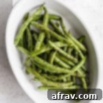 Air Fryer Green Beans served in a white oval dish with lemon wedges off to the side, highlighting the delicious result.