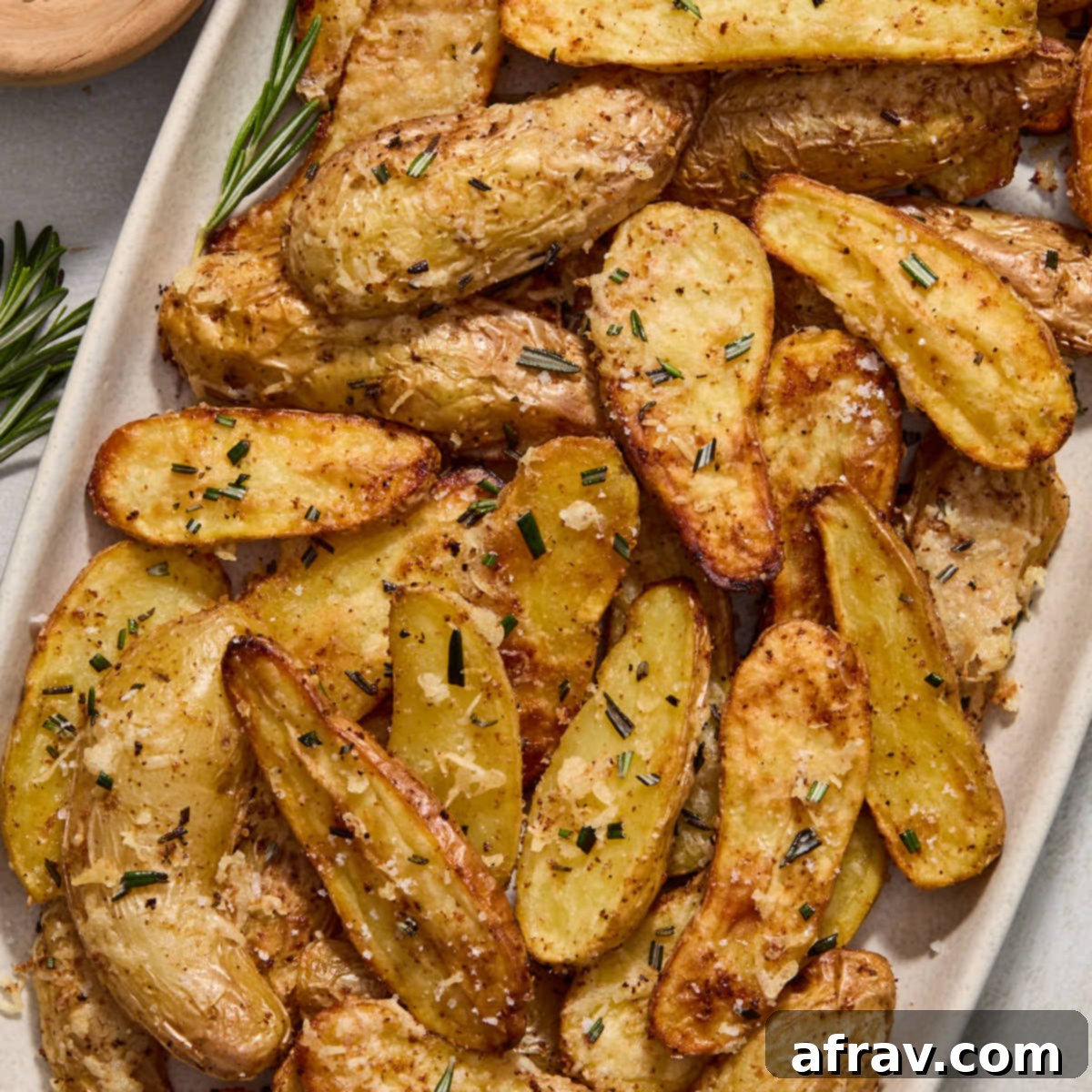 Effortless Air Fryer Side Dishes 13 Air fryer fingerling potatoes served on a platter and topped with fresh rosemary, looking gourmet and crispy.