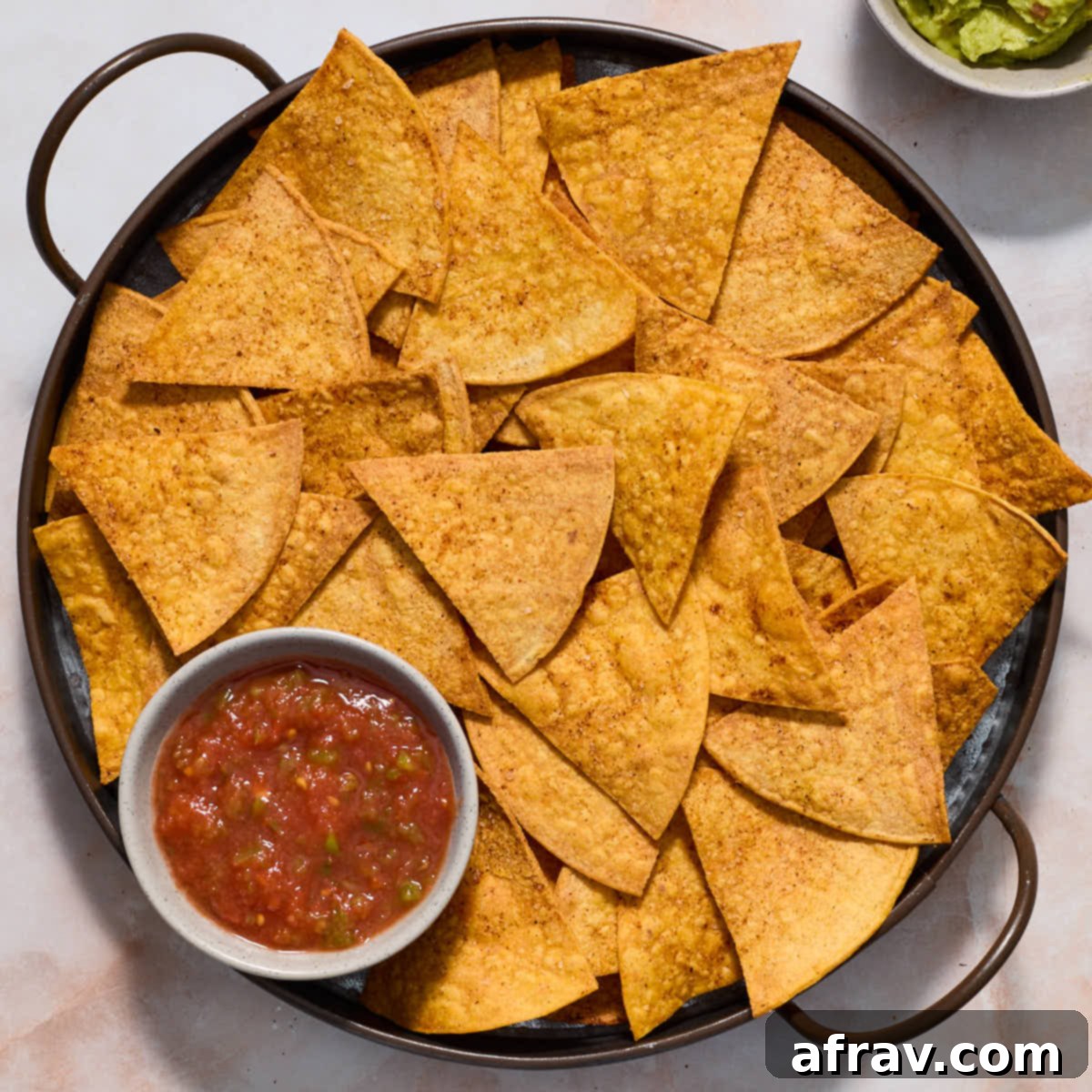 Effortless Air Fryer Side Dishes 14 Air fryer tortilla chips served on a round platter with salsa and guacamole on the side, perfect for dipping.