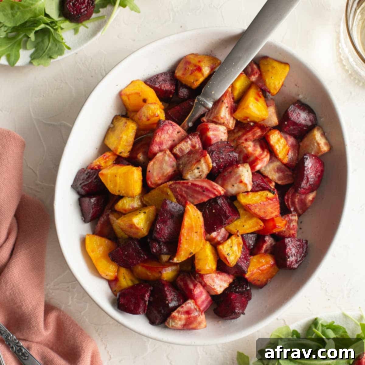 Effortless Air Fryer Side Dishes 7 Chopped beets (red, golden and candy cane) air fried and served in a white bowl with a spoon, showcasing colorful variety.