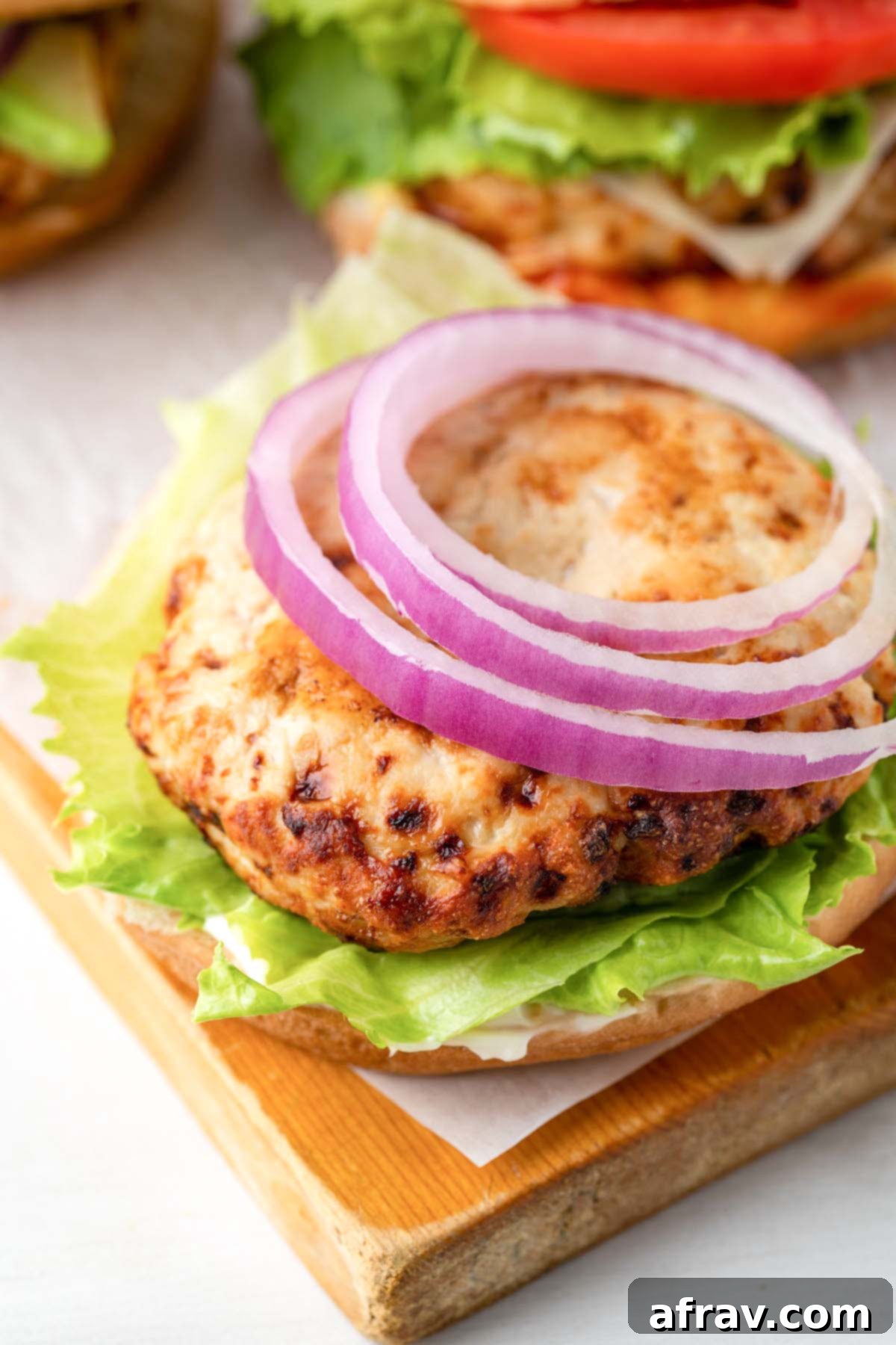 Perfectly Juicy Air Fryer Turkey Burgers 11 Turkey burger patty on a bottom bun with lettuce and onion.