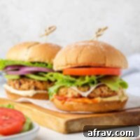 Two air fried turkey burgers with buns on a wood cutting board.