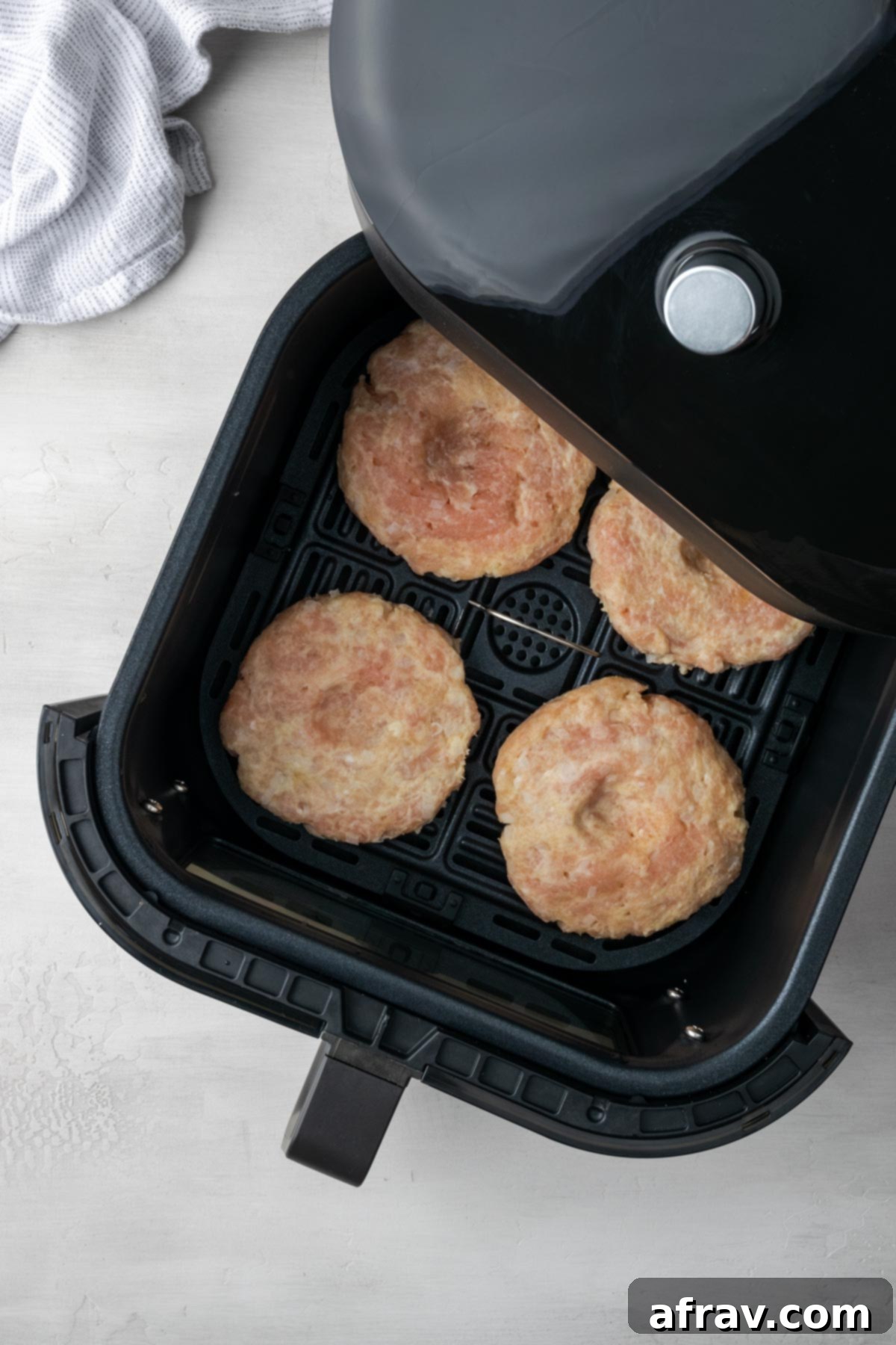 Perfectly Juicy Air Fryer Turkey Burgers 7 Turkey burger patties in an air fryer basket.