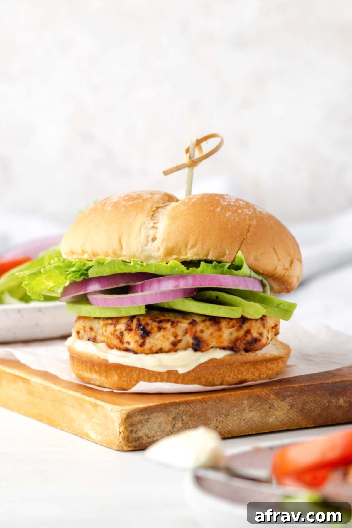 Perfectly Juicy Air Fryer Turkey Burgers 10 Air fryer turkey burger on a large bun topped with avocado, onion, and lettuce.