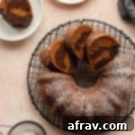 Pumpkin bundt cake on a round rack with a dusting of icing sugar on top.