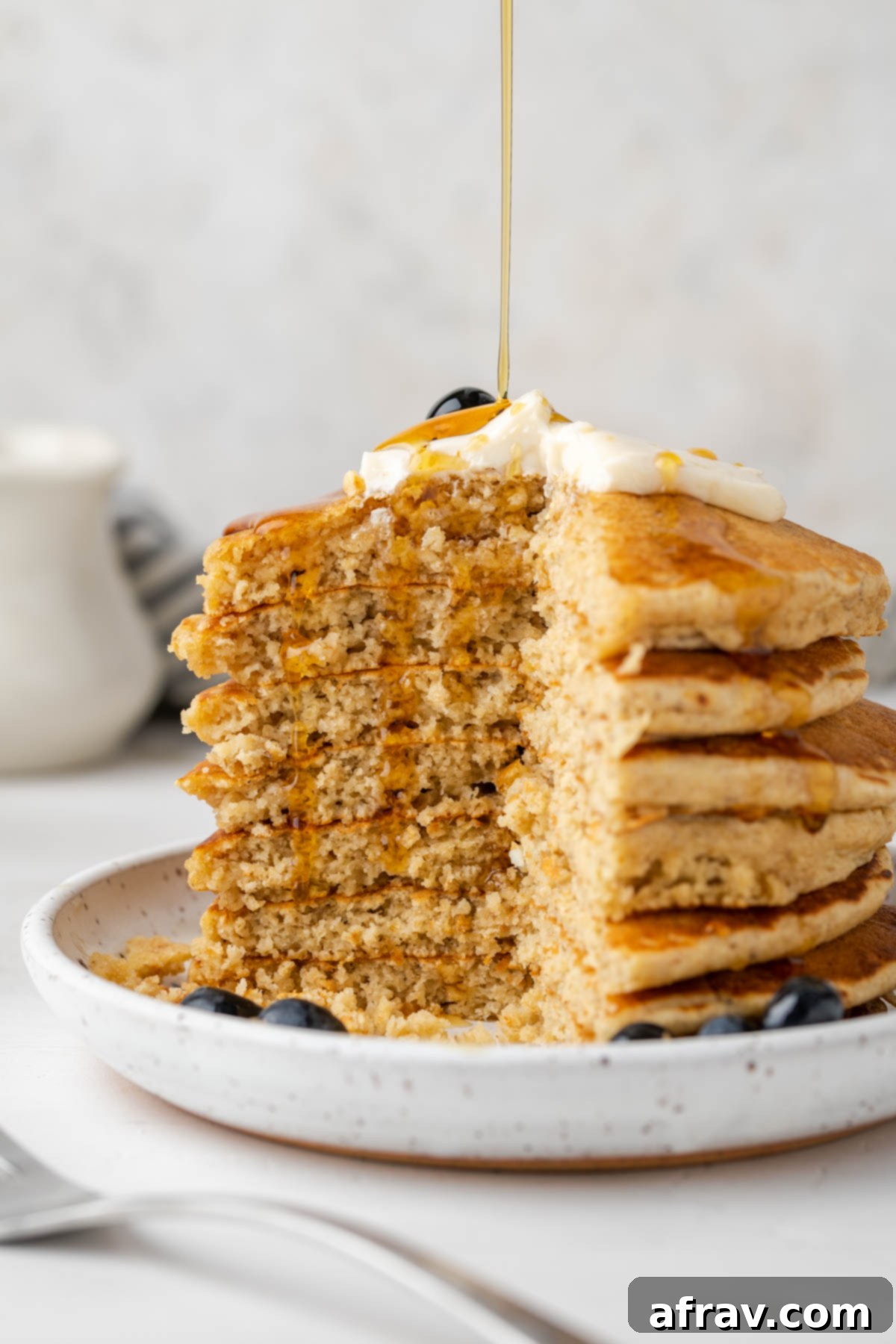 Stacked and cut oat flour pancakes with syrup dripping down the sides.