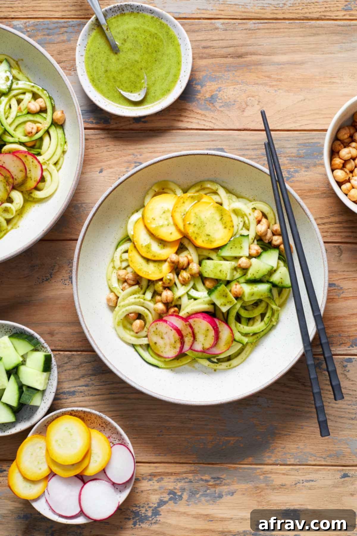 Zoodle Bowls 6 Zucchini noodles in a white bowl with chopsticks and toppings surrounding the bowl.
