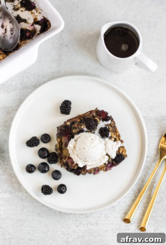 A perfectly baked slice of berry oatmeal with visible blueberries and blackberries, on a white plate.