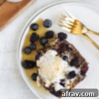 overhead view of a piece of baked berry oatmeal with coconut whipped cream and syrup on top, presented beautifully