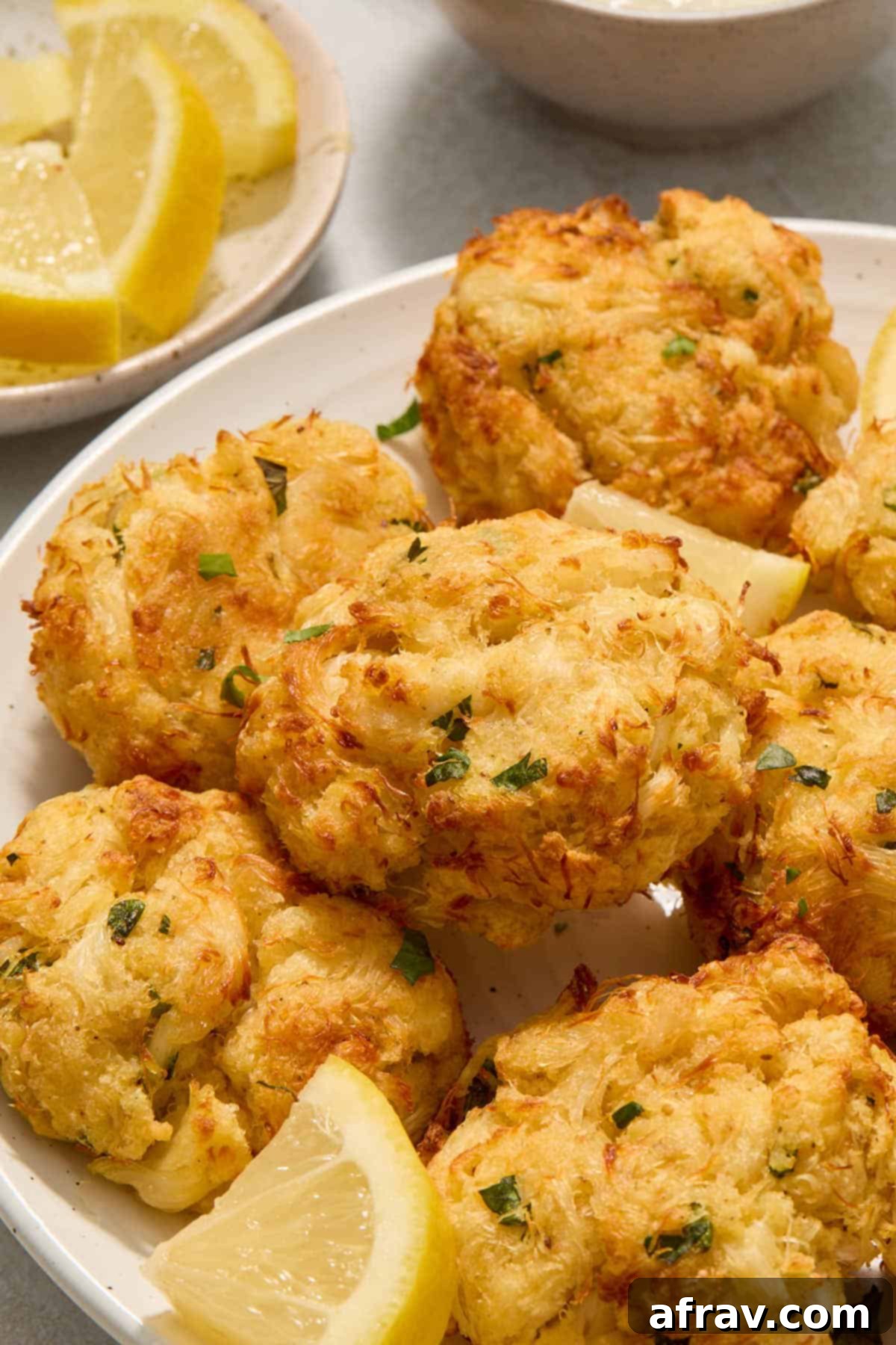 Crispy and Delicious Air Fryer Crab Cakes 2 Side view of crab cakes piled on a white plate, showcasing their golden-brown crust.