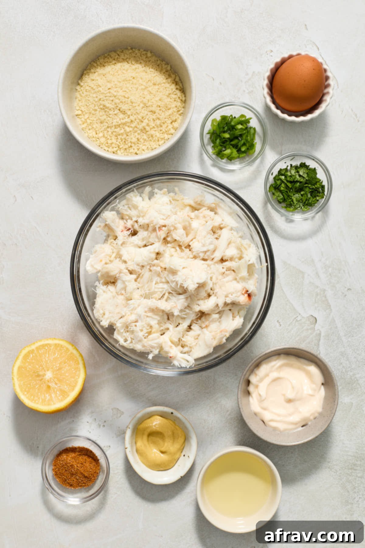 Crispy and Delicious Air Fryer Crab Cakes 3 Various crab cake ingredients, including lump crab meat, panko, and seasonings, arranged in separate bowls.