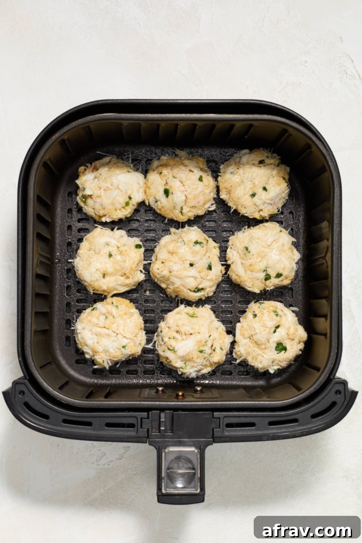 Crispy and Delicious Air Fryer Crab Cakes 6 Crab mixture formed into uniform patties and arranged in a single layer in an air fryer basket, ready for cooking.