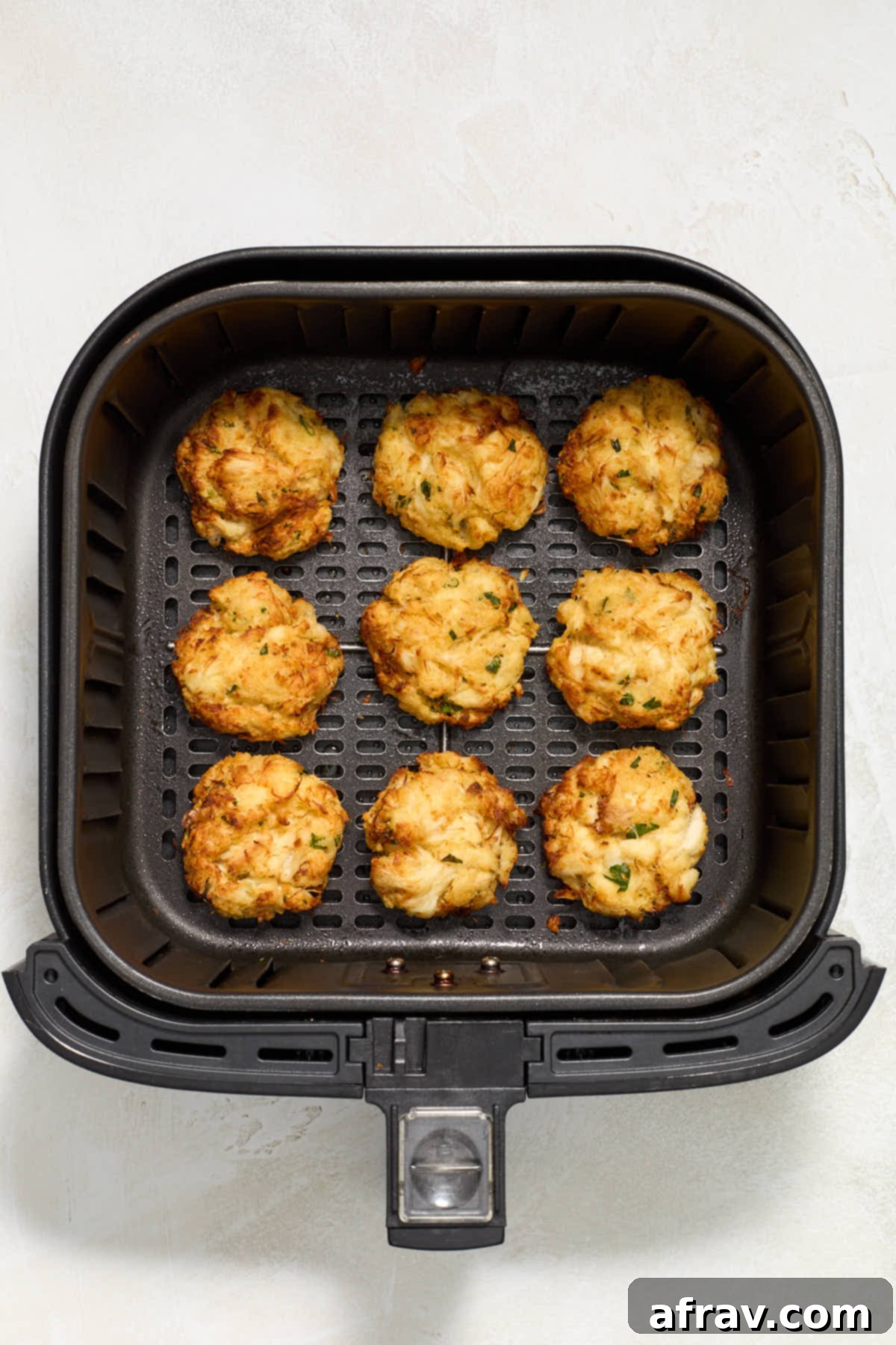 Crispy and Delicious Air Fryer Crab Cakes 7 Close-up of freshly air-fried crab cakes in the air fryer basket, showing their perfectly golden and crispy exterior.