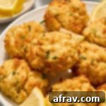 Crispy and Delicious Air Fryer Crab Cakes 10 Air fryer crab cakes served on a white plate with chopped parsley and lemon slices, ready to be enjoyed.