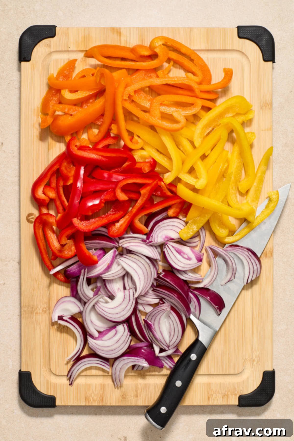 Golden Air-Fried Peppers and Onions 4 Bell peppers and red onions cut into slices on a wooden cutting board.