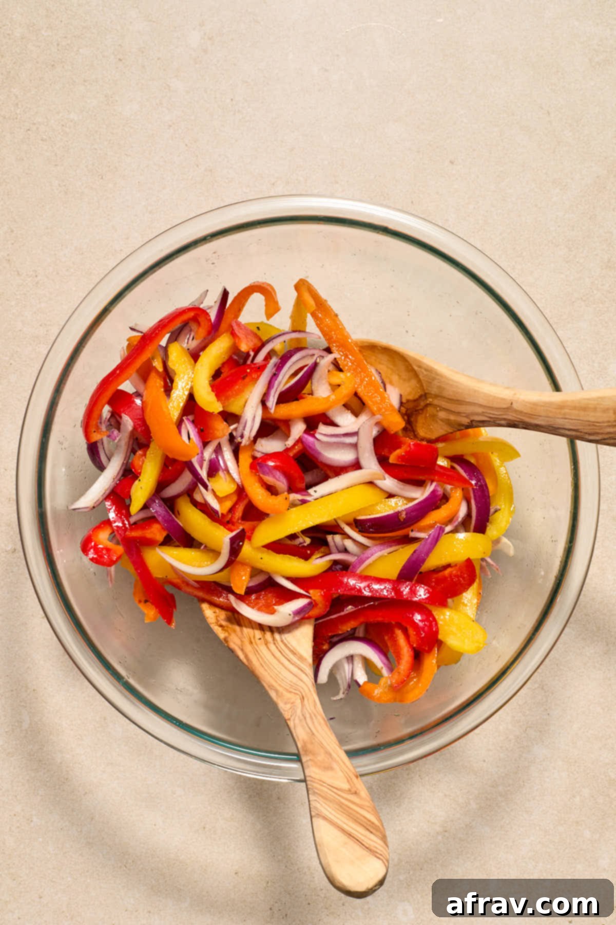 Golden Air-Fried Peppers and Onions 5 Sliced peppers and onions in a glass bowl and tossed together with oil and seasonings.