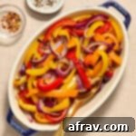 Golden Air-Fried Peppers and Onions 9 Air fryer peppers and onions served in an oval dish with a spoon inserted into it.