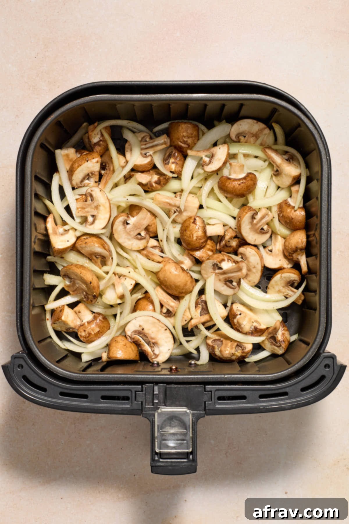 Crispy Air Fryer Mushrooms and Onions 6 Seasoned mushrooms and onions in the air fryer basket.