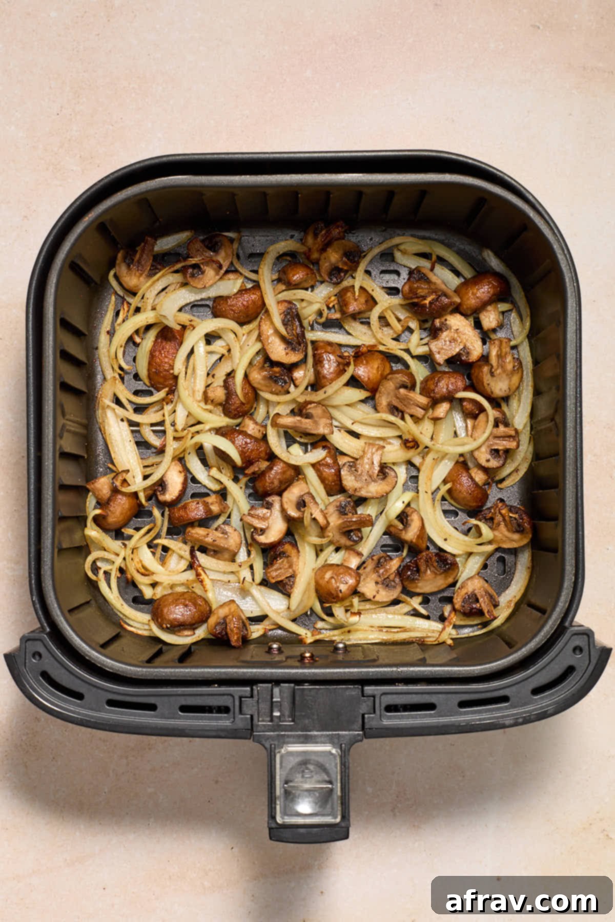 Crispy Air Fryer Mushrooms and Onions 7 Cooked mushrooms and onions in the air fryer basket.