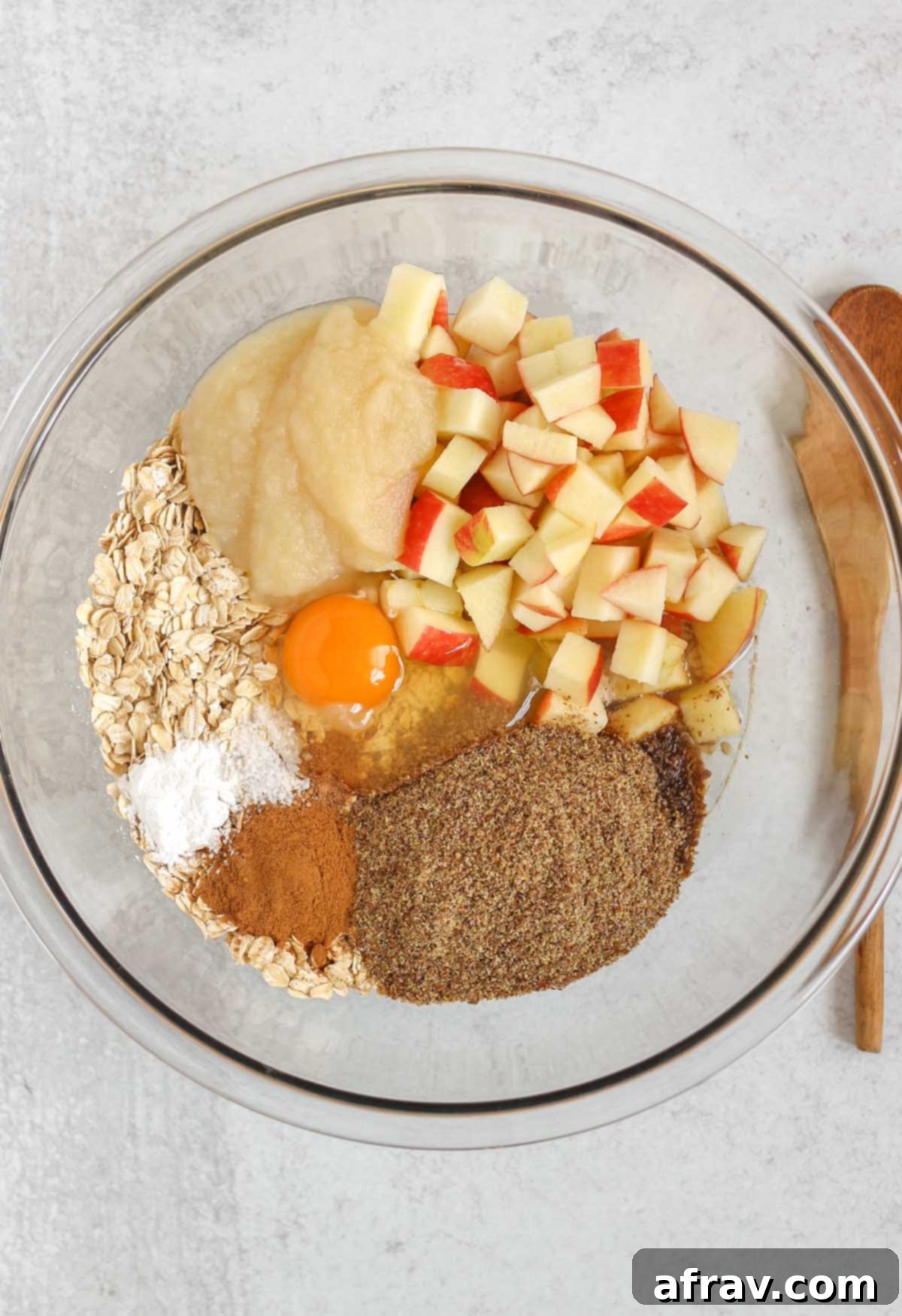 Ingredients for apple cinnamon baked oatmeal in a large glass mixing bowl before being mixed.